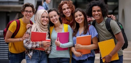 Multi-ethnic group of Latin American college students smiling at the university campus and looking at the camera - education concepts